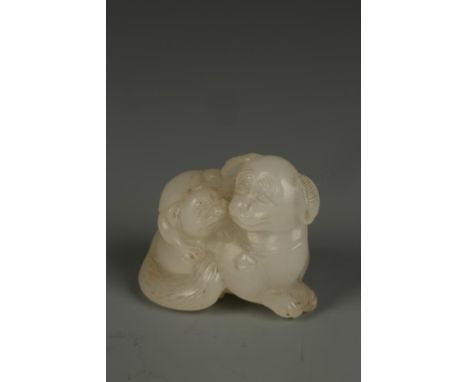 A CHINESE PALE CELADON JADE CARVING OF TWO DOGS, the adult with a pleased expression and the young climbing on its' back, Qin