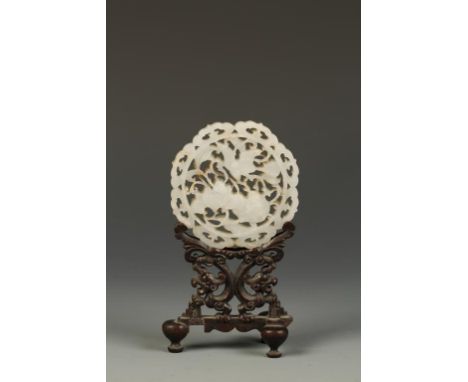 A CHINESE PIERCED CELADON JADE PLAQUE AND WOODEN STAND, the openwork plaque carved with flowers and foliage within an ogee bo