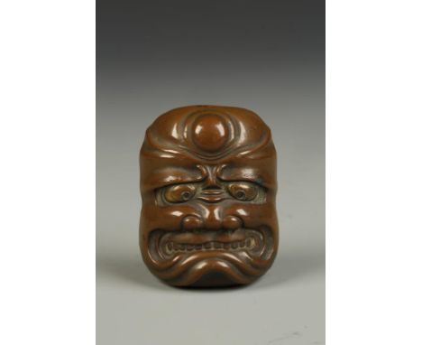 A JAPANESE BRONZE MINIATURE MASK with a grimacing expression and gilt eyes, Meiji, 2" high