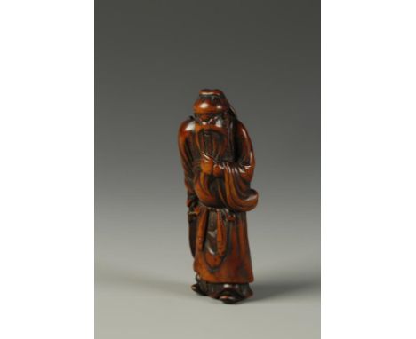 AN EARLY JAPANESE WOOD NETSUKE by Hachigyoku, showing Kanu standing upright and stroking his beard, the surface with a rich p