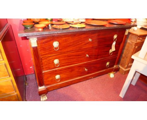 An Empire style mahogany commode with marble top over three drawers on gilt paw feet
