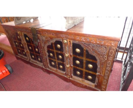 A teak Indian trunk with brass surmounts and handles