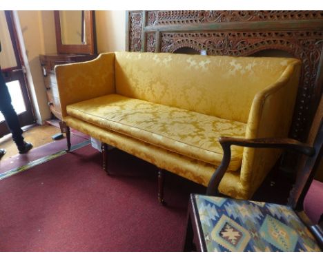 A Regency three seater sofa upholstered in golden damask, raised on turned mahogany supports terminating in brass castors 