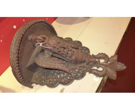 A carved South East Asian hardwood wall bracket decorated with an exotic bird holding a snake in its mouth 