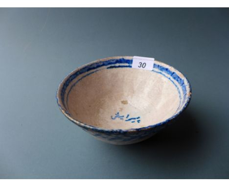 A Qujar period mid 19th century Persian ceramic bowl with blue and white glaze and writing inside 