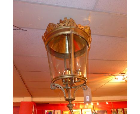 A large brass hanging lantern, the top with castle decoration over four curved glazed panels 