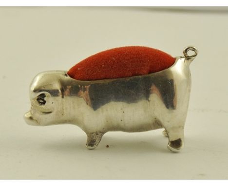 AN EDWARDIAN STYLE SILVER COLOURED METAL PIN CUSHION fashioned as a pig with ring tail and red velveteen inset, unmarked, 36m