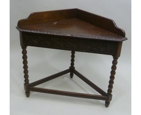 AN OAK CORNER TABLE with plain galley back, 17th Century design carved frieze on bobbin turned supports, 91cm 