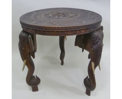 AN INDIAN CARVED WOOD OCCASIONAL TABLE raised on three elephant head and trunk supports, 45cm diameter 