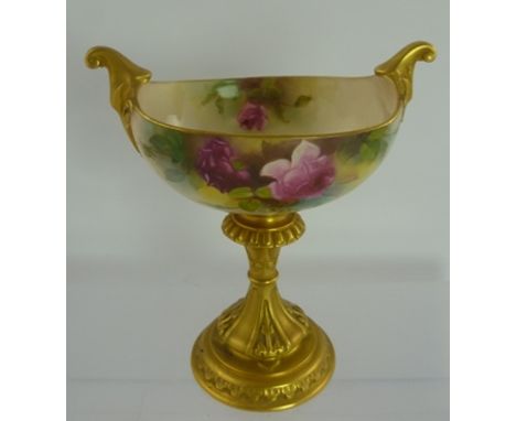 A ROYAL WORCESTER PORCELAIN VASE, having oval bowl with twin upscrolled gilt handles, painted with pink roses, on cast ringed