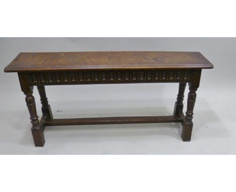 AN ELIZABETHAN DESIGN OAK BENCH, chip carved and moulded seat on arch carved frieze, carved supports with plain stretchers, 1