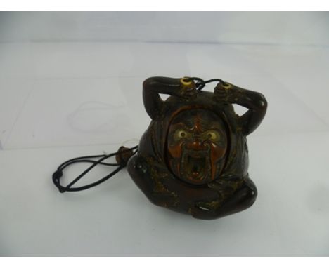 A JAPANESE MEIJI PERIOD CARVED GOURD INRO in the form of a screaming rotund figure his face being the cover attached to a cor