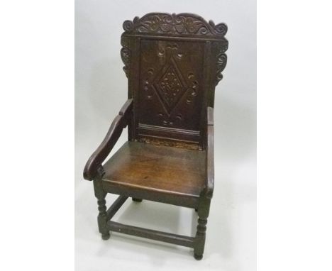 A PART 17TH CENTURY OAK WAINSCOT CHAIR the back with carved crest rail and lozenge panel back, scroll open arms on turned for