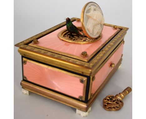 An early 20th century Swiss gilt metal and enamel table music box with key, the rectangular casket centred by a carved ivory 