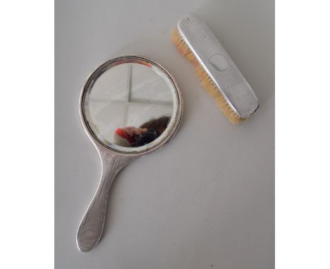 A two piece silver dressing set comprising a mirror and a brush both with engine turned decorative scrolling (2)