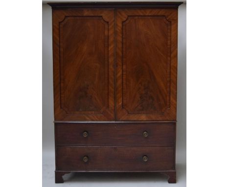 A George III mahogany wardrobe with cavetto molded cornice above a pair of panelled doors over a mock drawer and a long drawe