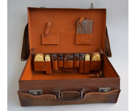 An early 20th century gent's leather travel suitcase with fitted leather interior and accessories to include button hook, twe