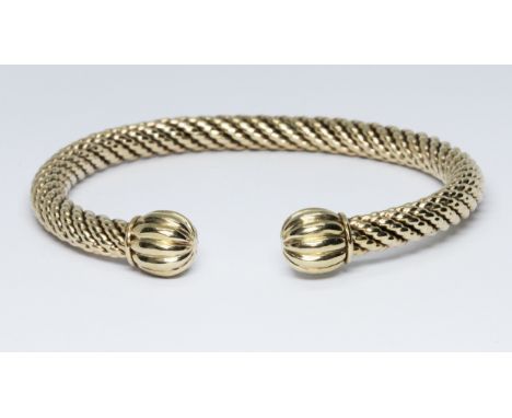 A 9ct gold bangle, twist form with fluted terminals, 9ct gold import marks, diameter approx. 6cm, wt. 21.2g.  