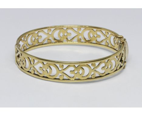 A 9ct gold pierced bangle, wt. 18.2g, diam. 5.5cm.  Condition - slight play in hinge, clasp and safety clips working but slig