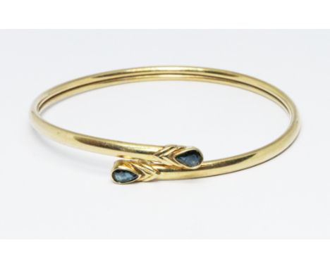 A hallmarked 9ct gold sapphire bangle, wt. 7.9g, diam. 6cm. Condition - general wear.