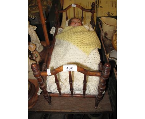 Good quality miniature babies cot with turned baluster rails on casters together with a Koppelsdorf German bisque headed doll