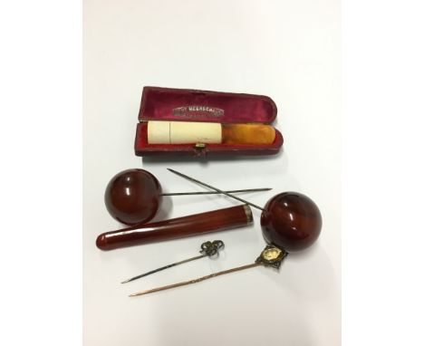 A bag containing a quantity of stick pins, some Bakelite together with a cased amber and Meerschaum cigar holder.