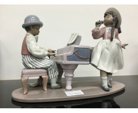 A Lladro china figure modelled as a Young Girl and Boy singing and playing the piano (girl's hair plait re-glued).
