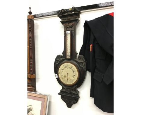 A late 19th century carved oak cased aneroid barometer decorated with flowers and drapes (no glass).
