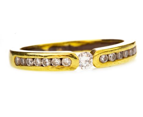 DIAMOND BAND, set with a central round brilliant cut diamond of approximately 0.07 carats on channel set diamond shoulders, m