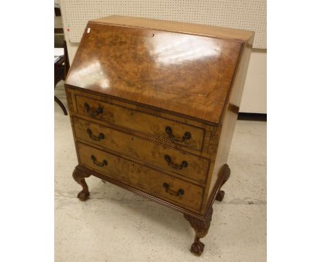 A mid 20th Century walnut bureau with sloping fall enclosing a basic fitted interior over three long drawers on claw and ball