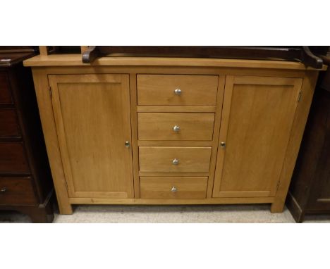 A modern light oak sideboard with four central drawers flanked by two cupboard doors, 140 cm wide x 40 cm deep x 90 cm high, 