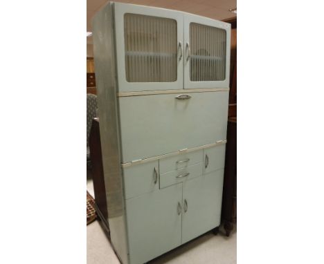 A 1950's painted kitchen cabinet, the two semi-frosted glazed doors enclosing shelf over a sloping fall, enclosing a basic fi