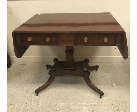 A Regency mahogany sofa table, the rounded rectangular top with plain drop leaves above two frieze drawers with circular cast