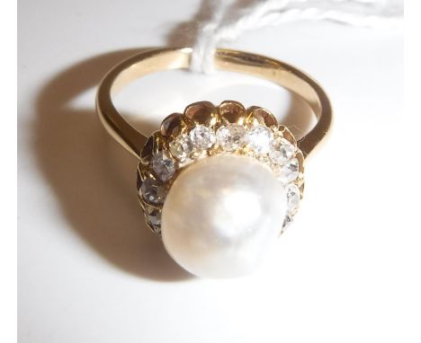 A gold-mounted (un-marked) pearl and diamond dress ring, the central pearl (approx size 17), within a band of seventeen small