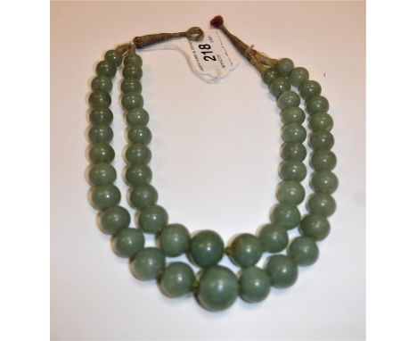 A 19th Century Chinese jade two strand bead necklace, knotted and with thread fastening, largest bead 1.8cm diameter smallest