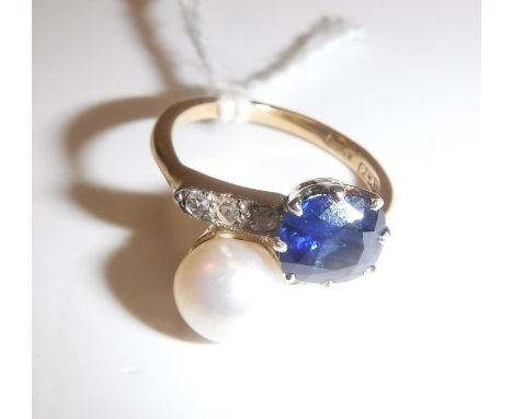 An 18 carat gold and platinum mounted cross over ring set with pearl (size 9) and single sapphire, approx .75 carat, with thr