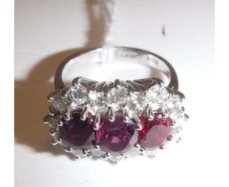 An 18 carat white gold mounted ladies dress ring set with three central rubies within a band of seventeen diamonds, each appr