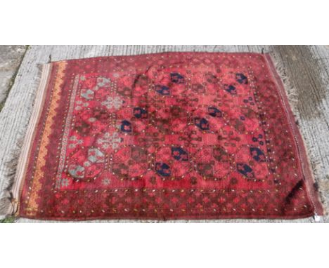 A Turkamen rug, the central panel set with repeating elephant foot style medallions on a red ground, within a red and brown s
