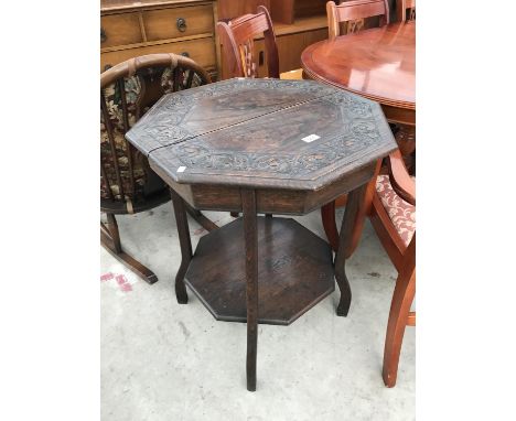 AN OCTAGONAL OAK OCCASIONAL TABLE WITH CARVED TOP AND LOWER SHELF 