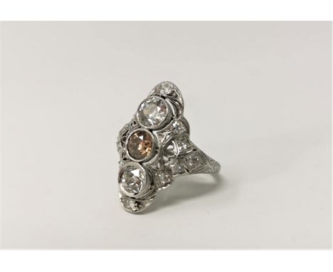 An Art Deco white metal diamond dress ring with 3 central diamonds mounted vertically, the middle stone tinted brown, each ap