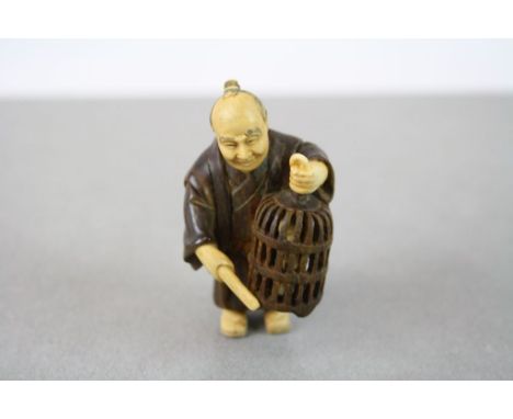 A vintage signed carved chinese netsuke of an oriental man with bird cage.