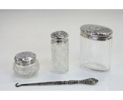 A collection of hallmarked silver items to include three silver topped vanity jars and a button hook with silver handle.