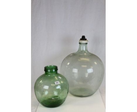 A large clear glass carboy converted to lamp and one other carboy.