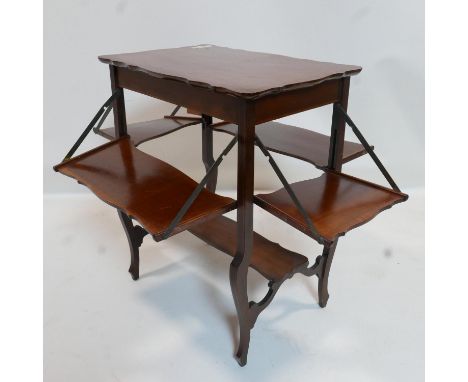 An Art Nouveau mahogany lamp table with folding shelves and walnut cross banding 