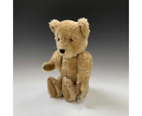 A Chiltern Toys golden plush Teddy bear, orange glass eyes, velvet paws with embroidered claws and nose. Height: 44cm approx.