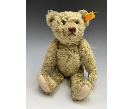 A Steiff bear. Golden fur, glass eyes, stitched nose and claws, felt pads. Ear tag numbered 004261. Height 28cm.