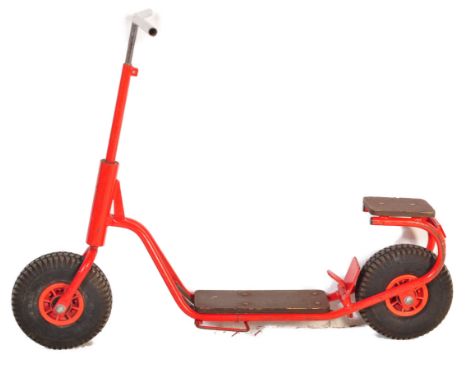 A vintage 20th Century children's scooter finished in red with wooden plinth standing borders and stepped back. Thick rubber 