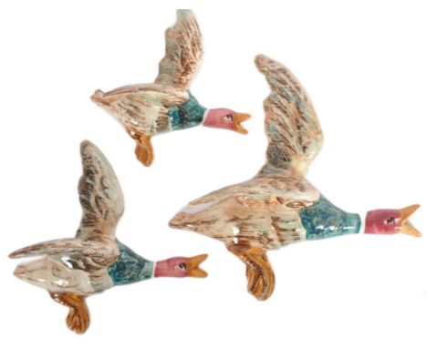 A graduating set of three vintage 20th Century studio art pottery wall plaques in the form of flying Mallard ducks. Each with