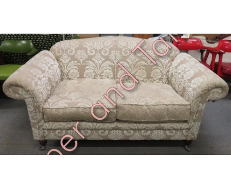 A two seater sofa upholstered in Designer Guild fabric, on four turned wooden feet with casters, 170cm wide max