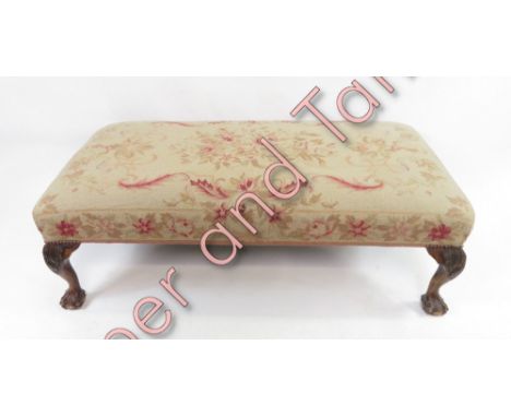 A long, low stool with florally decorated tapestry seat, on four ball and claw feet, 119cm long, 57cm wide, 38cm high